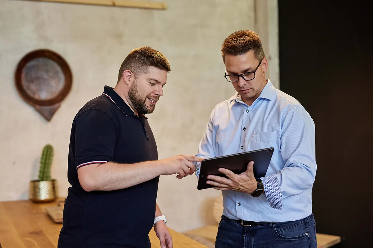 Zwei IT-Berater besprechen IT-Sicherheits-Konzept am Tablet – IT-Sicherheit für KMU