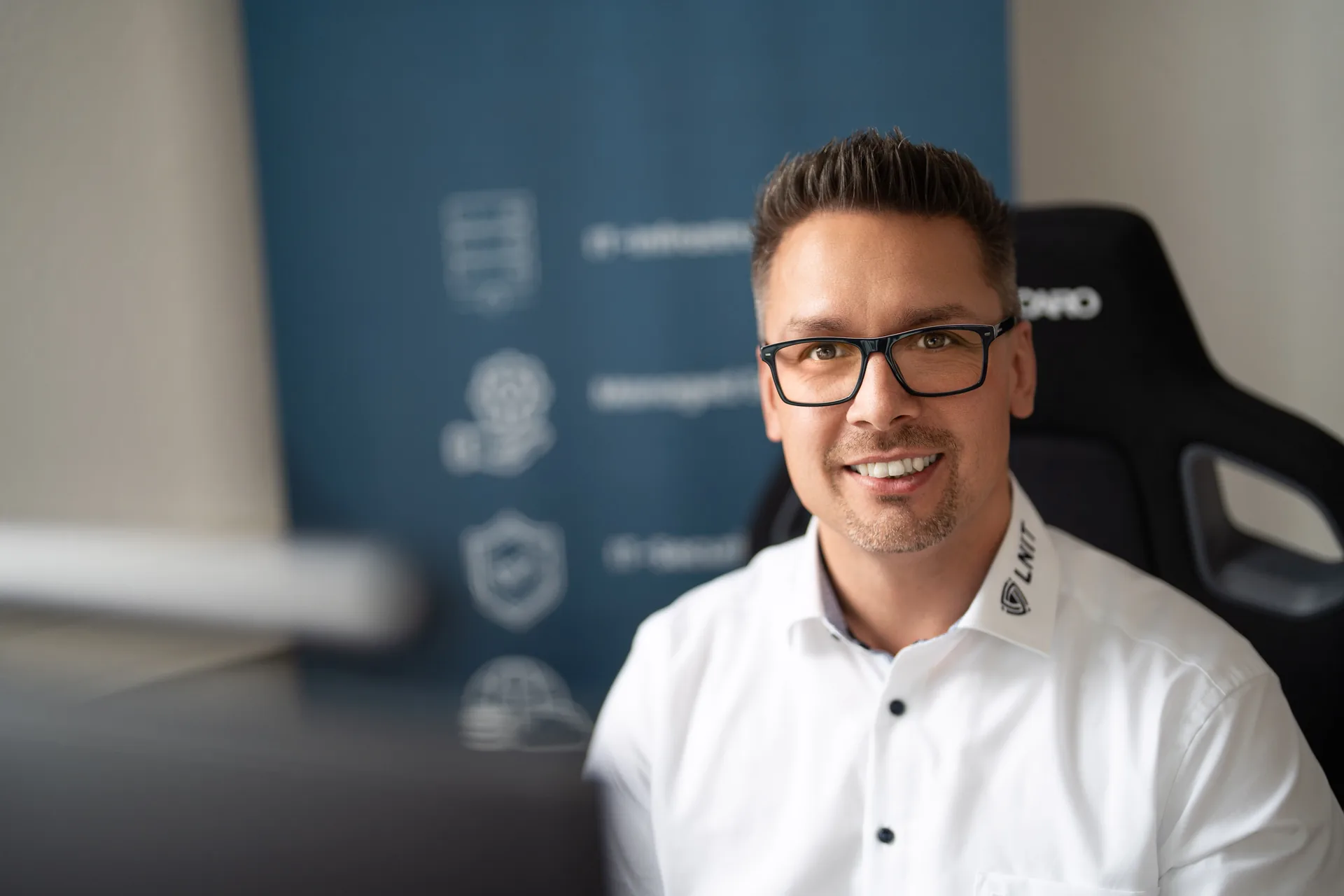 Lars Neumann, Inhaber von LNIT, lächelt im weißen Hemd im Büro in Diekholzen in die Kamera